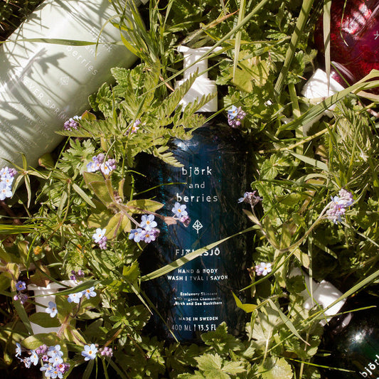 BJÖRK & BERRIES Fjällsjö Hand & Body Wash / Duschgel, bottle on flowers