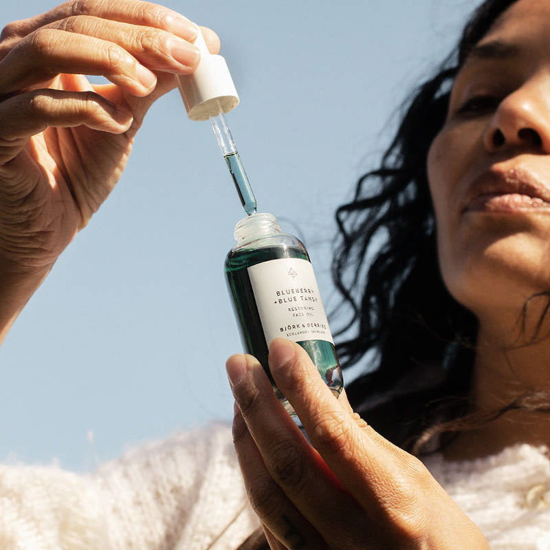 BJÖRK & BERRIES Blueberry + Blue Tansy Face Oil. Woman with product.